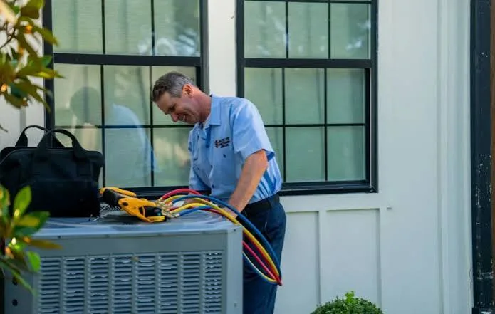 HVAC technician servicing a residential outdoor condenser in Abington