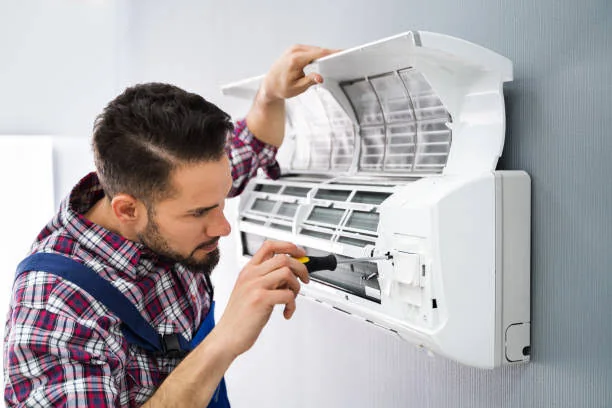 Technician performing maintenance on a wall-mounted air conditioning unit