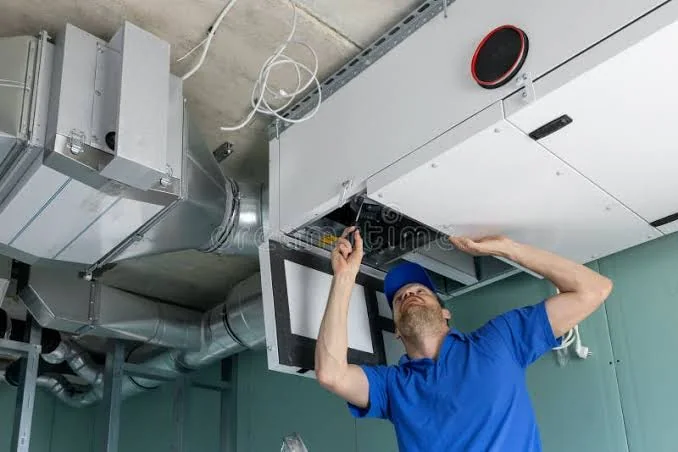 HVAC technician inspecting indoor ductwork and air-handling equipment